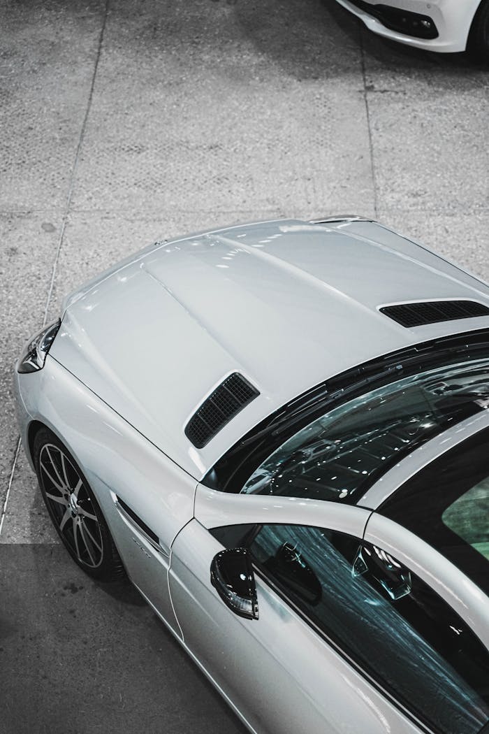Close-up of a sleek silver luxury car in a dealership showroom, showing pristine design and elegance.